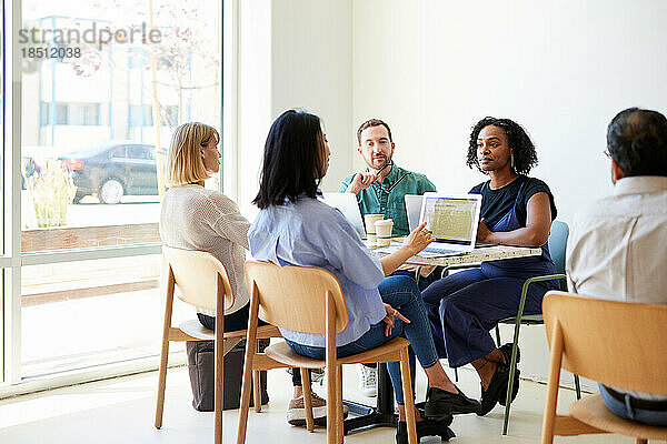 Gemischtrassige Kollegen planen Strategie  während sie im Café sitzen