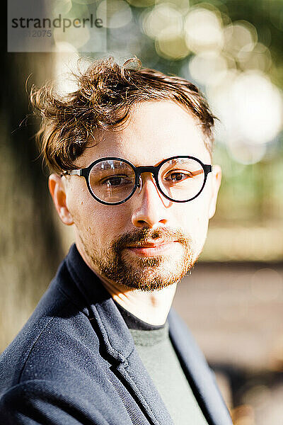 Stilvoller lockiger Mann mit Brille im Park