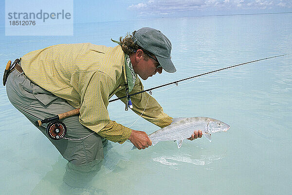 Ein Salzwasser-Fliegenfischer hält einen Trophäen-Grätenfisch.