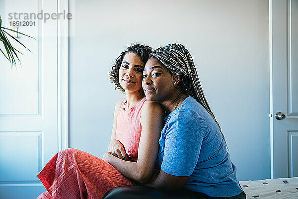 Porträt eines selbstbewussten lesbischen Paares  das zu Hause im Schlafzimmer sitzt
