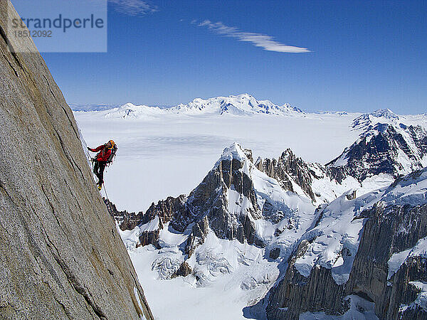 Ein Kletterer erklimmt die steile Nordwand des Torre Egger mit den Gipfeln des Cerro Rincon darunter und den Gletschern des südlichen Pennsylvania