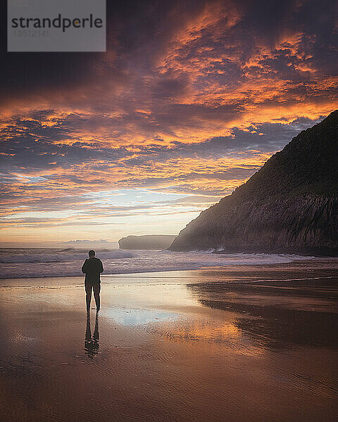 Mann beobachtet den Sonnenaufgang vor dem Meer