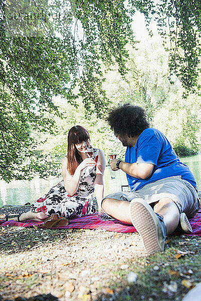 Entspanntes Paar beim Weintrinken am Seeufer im Englischen Garten  München  Deutschland