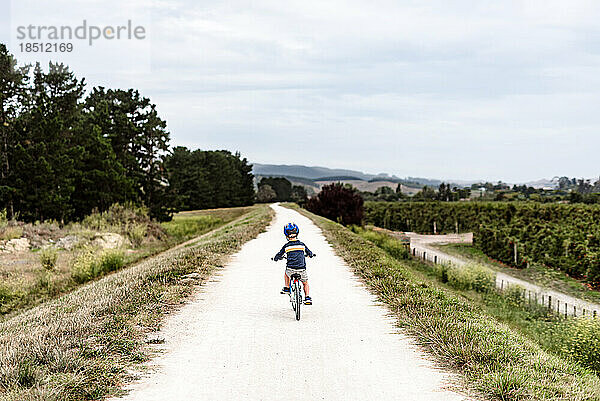 Kleiner Junge fährt Fahrrad auf abgelegenem Weg in Neuseeland