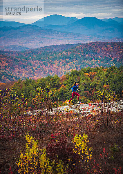 Frau beim Trailrunning in den Bergen mit Laub im Herbst