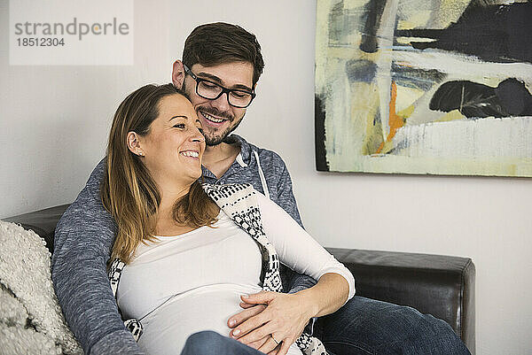 Schwangere Frau mit ihrem Mann auf dem Sofa  München  Deutschland