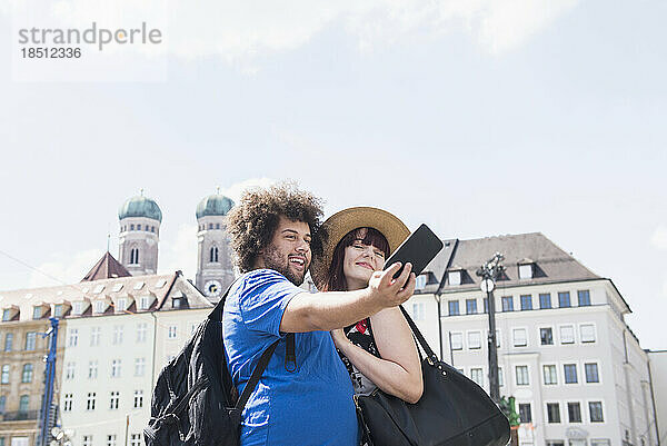 Paar macht ein Selfie mit einer Handykamera vor der Liebfrauenkathedrale in München