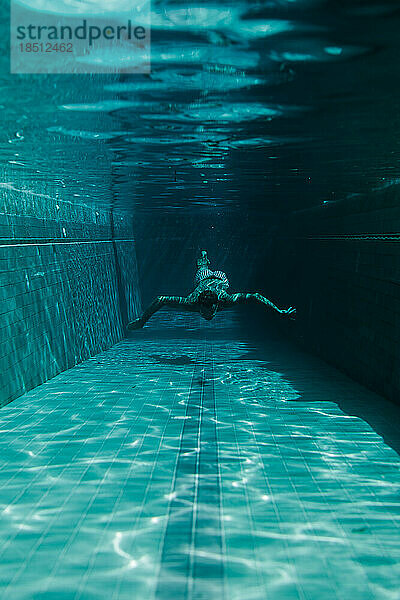 Mann schwimmt im Pool unter Wasser.