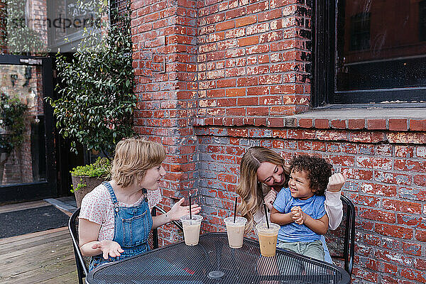 Zwei erwachsene Frauen im Straßencafé mit gemischtrassigem Kleinkind