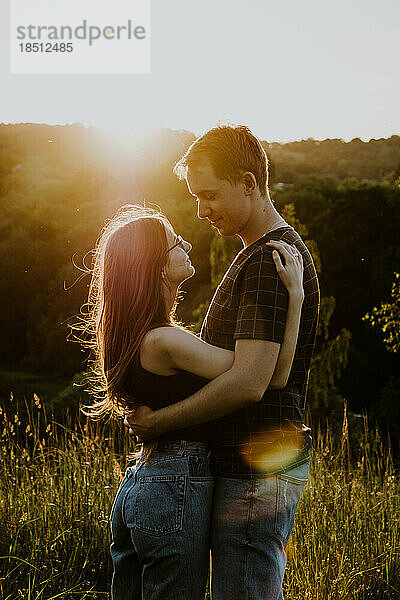 Mann und Frau umarmen sich im Sommer im Park vor der Sonne