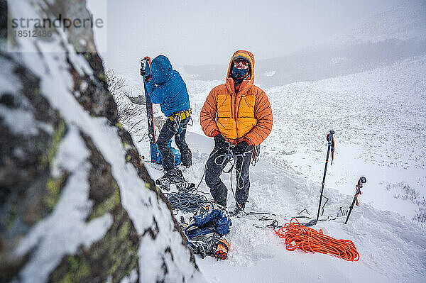 Men preparing gear for winter ski-mountaineering in puffy jacket