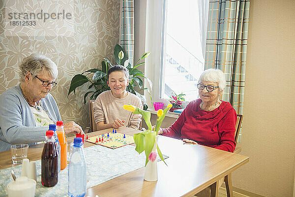 Mädchen spielt Brettspiel mit älteren Frauen im Altersheim