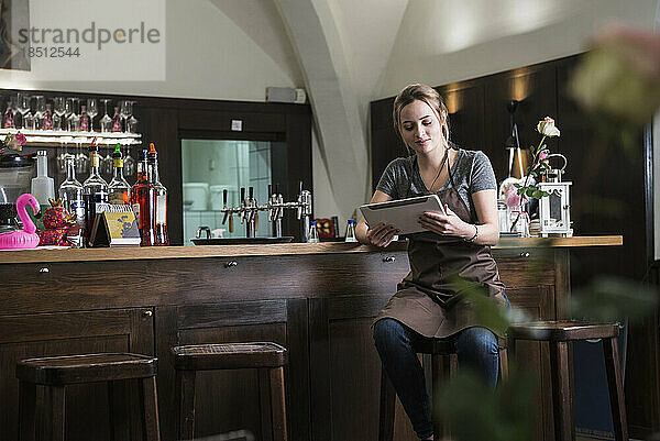 Restaurantbesitzer nutzt Tablet  während er an der Bartheke sitzt