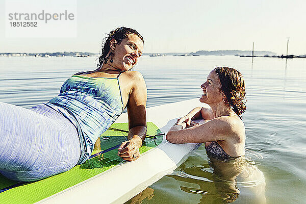 Zwei junge Freundinnen entspannen sich auf dem Standup-Paddle-Board in Casco Bay