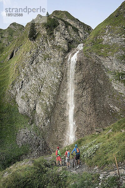 Drei Mountainbiker-Freunde beobachten Wasserfall  Zillertal  Tirol  Österreich