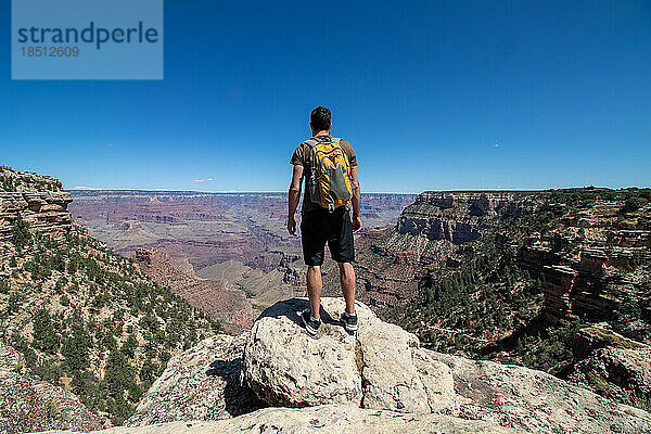 Mann mit gelbem Rucksack am Rande des Colorado Canyon.