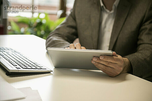 Mittelteil eines Geschäftsmannes mit digitalem Tablet in einem Büro  Bayern  Deutschland