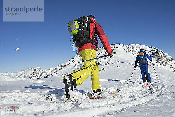 Rückansicht von Skifahrern  die in Richtung Berg laufen