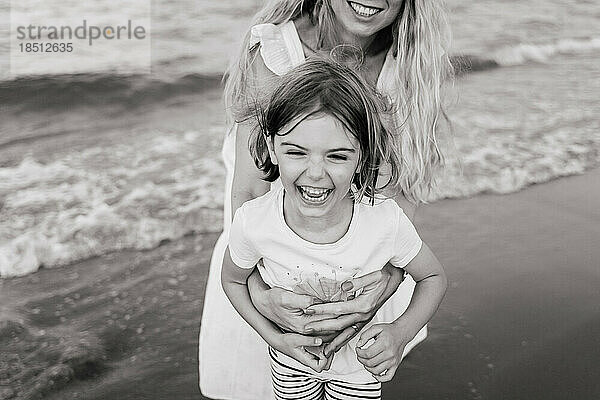 Glückliches kleines Mädchen mit Quads lacht fröhlich am Strand  spielt