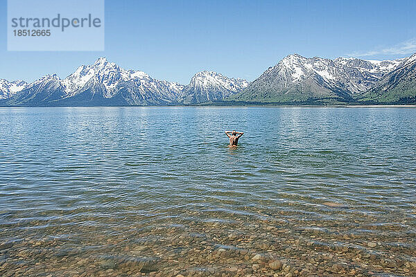 Mann steht im tiefen Wasser eines Alpensees