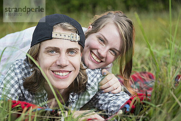 Porträt eines jungen Paares  das auf einer Wiese liegt und lächelt  Bayern  Deutschland