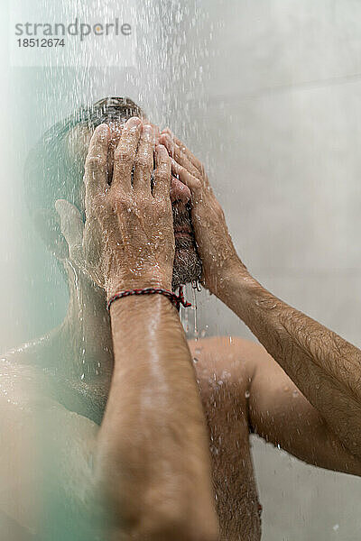 Mann mittleren Alters unter der Dusche  Wassertropfen.