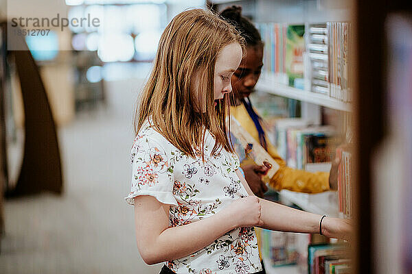 Friends looking at books on a shelf