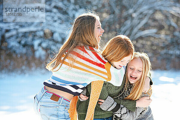 Drei glückliche  schöne Teenager-Mädchen draußen im Schnee.