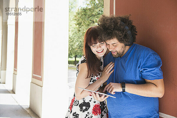 Glückliches junges Paar mit digitalem Tablet und Kopfhörern