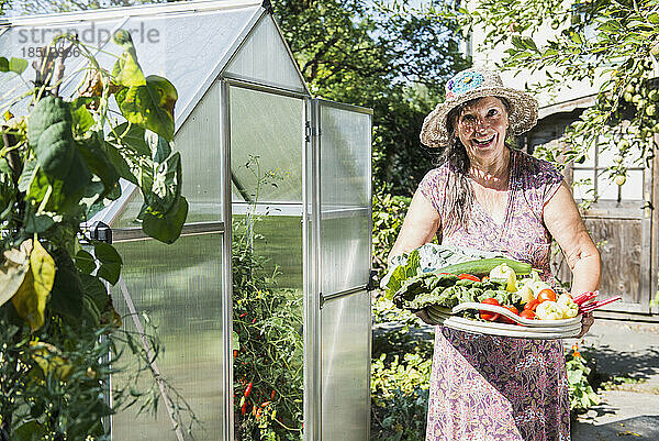 Ältere Frau mit einem Korb mit geerntetem Gemüse in einem Garten  Altötting  Bayern  Deutschland