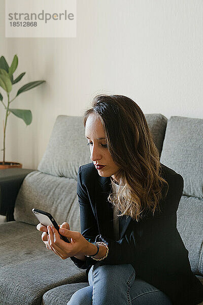 Geschäftsfrau auf einer Couch mit einem Mobiltelefon