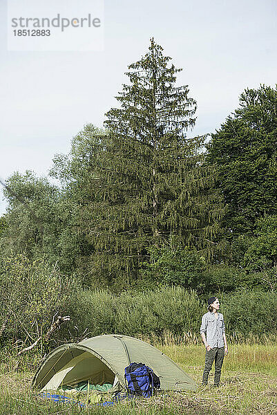Teenager steht in der Nähe seines Zeltlagers im Wald  Bayern  Deutschland