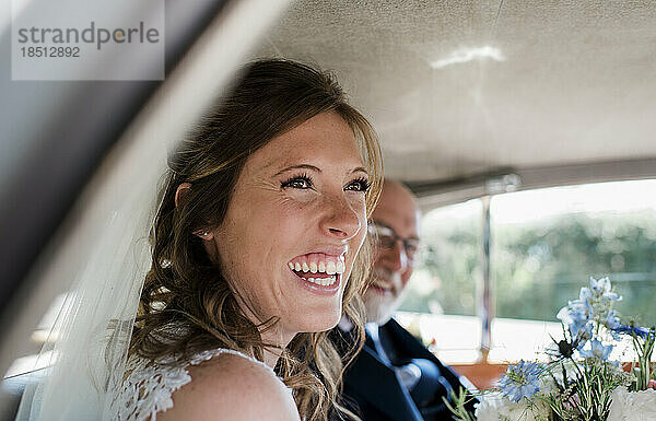 Eine Braut lacht an ihrem Hochzeitstag in ihrem Auto