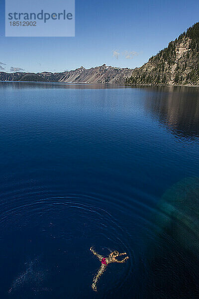 Eine junge Frau schwimmt im kalten  klaren Wasser des Crater Lake.
