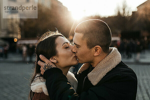 Mann und Frau küssen sich unter der Herbstsonne im Zentrum von Prag