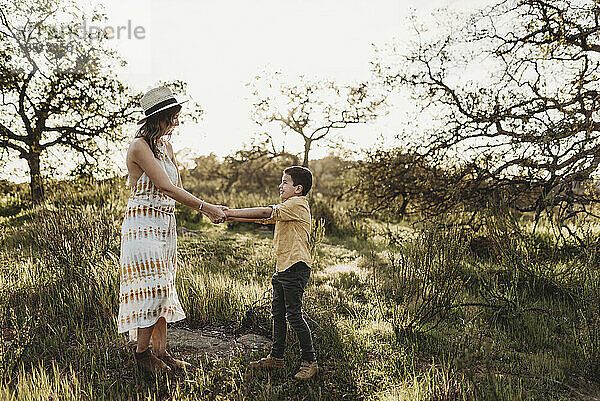 Junge Mutter und Sohn halten Händchen und spielen auf dem kalifornischen Feld