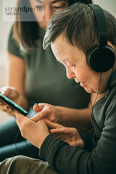 Ältere Frau mit Down-Syndrom  Assistentin hilft beim Telefonieren