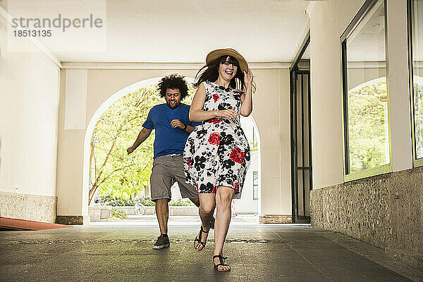 Glückliches junges Paar läuft im Gebäudekorridor