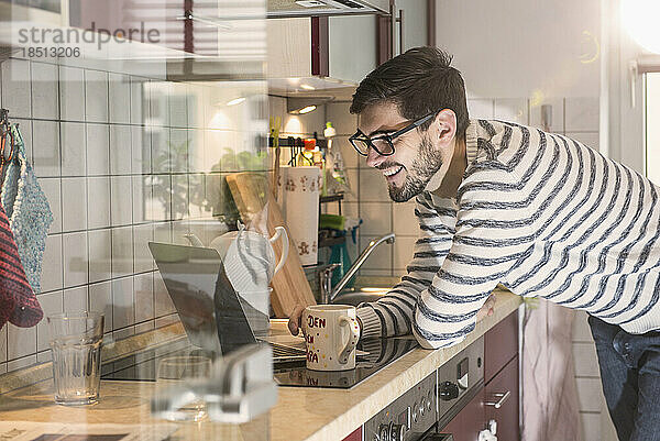 Mann mit Laptop und Tasse in der Küche  München  Deutschland