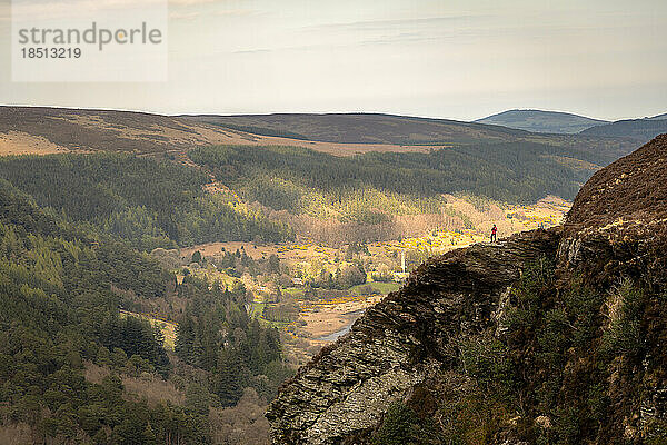 Frau auf dem Berggipfel  die den Blick auf den See in Glendalough bewundert