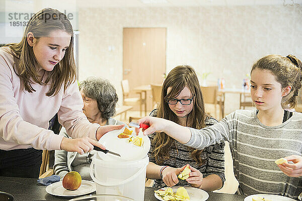 Ältere Frau mit Mädchen schält Apfel im Pflegeheim