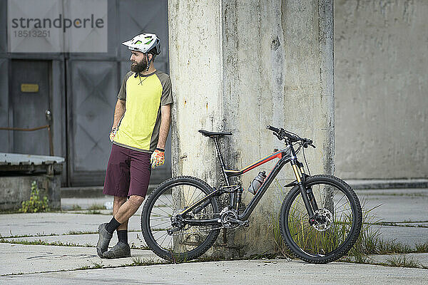 Mountainbiker steht in der Stadt neben seinem Fahrrad
