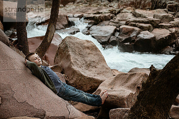 Kind entspannt sich bei einer Frühlingswanderung neben dem Wasserfall