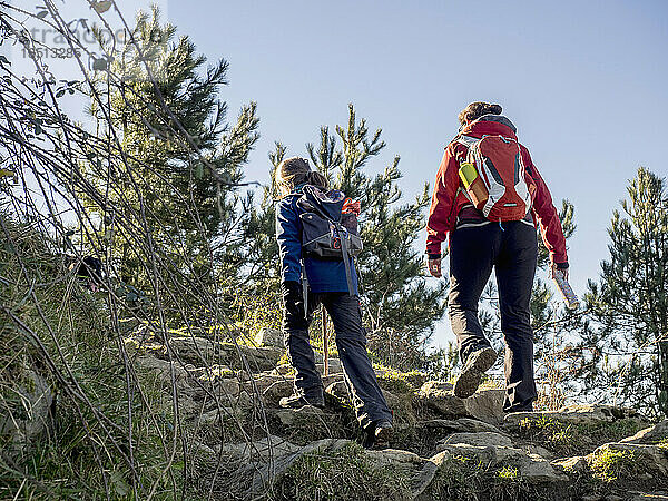 Frau und Mädchen gehen auf einem Singletrail zum Gipfel des Berges