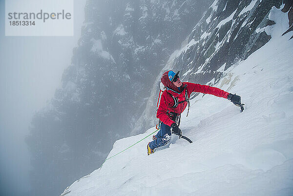 Eiskletterer klettert im Winter auf eine steile Eiswand