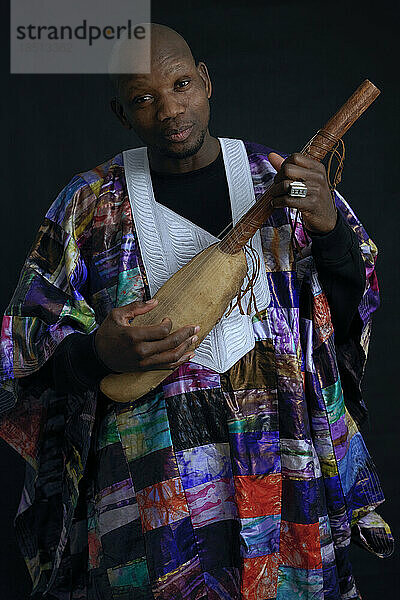 Afrikanischer Musiker mit Saiteninstrument und typischer Kleidung.