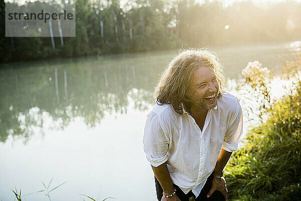 Fröhlicher Mann mit langen Haaren  der am Fluss lacht  Bayern  Deutschland