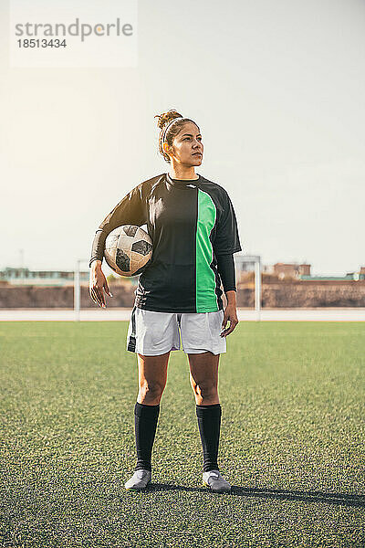 Porträt einer glücklichen Fußballspielerin mit einem Fußball.