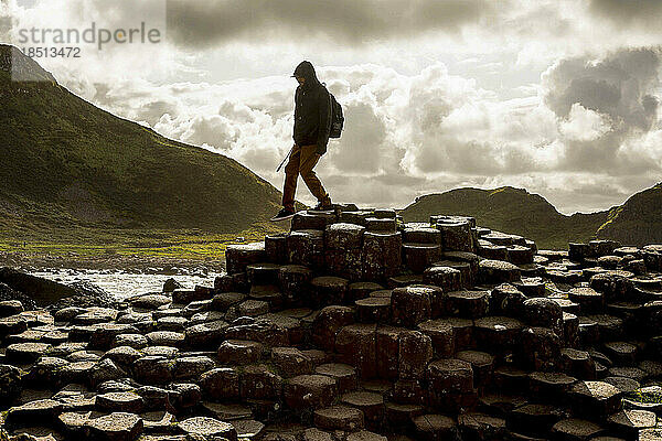 Der Mensch spaziert zwischen einzigartigen sechseckigen Felsen in Irland
