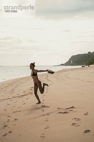 Eine junge Frau auf dem Meer hat Spaß und springt.